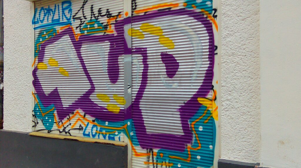 Graffiti du Crew 1UP à berlin sur un store, couleurs du graff: chrome, violet, jaune et du bleu pour le fond. 